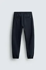 Pantalón jogger negro de corte slim fit, confeccionado en tejido de algodón con cintura elástica ajustable con cordón, bolsillos frontales y traseros de vivo, y bajo con puño elástico.