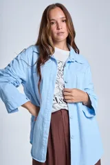 Sobrecamisa negra de gabardina con cuello camisero, cierre frontal con botones, mangas largas con puños abotonados y bolsillos de parche en el pecho.