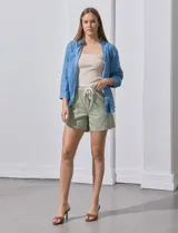 Camisa celeste de tencel con cuello con solapa, escote en V, abertura central con botones, bolsillo aplicado en el frente y ruedo desflecado.