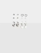 Set de seis pares de aros plateados con diferentes diseños: aros tipo argolla, aros con forma de corazón, aros con perlas y aros con strass.
