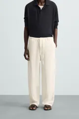 Pantalón de lino color crudo, de corte ancho, con cintura elástica ajustable con cordón, bolsillos laterales y trasero.