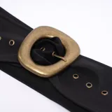 Cinturón ancho de color negro con hebilla cuadrada dorada y múltiples ojales metálicos.
