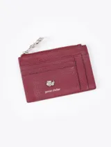 Tarjetero de cuero vacuno color bordó con aplique metálico de flor y tiracierre con diseño exclusivo.