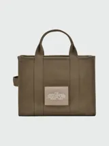 Bolso tote mediano color beige con estampado frontal del logo "The Tote Bag Marc Jacobs" en blanco. Tiene doble asa corta y correa larga extraíble de tela azul marino.