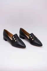 Chatitas negras de cuero con punta fina y apliques de tachas doradas.