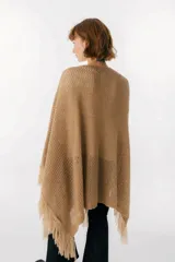 Ruana de punto color beige con cuello alto y flecos.