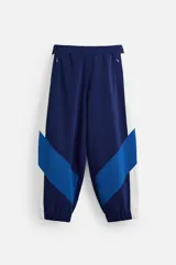 Pantalón deportivo azul marino con paneles laterales blancos y azules, corte relaxed fit, cintura elástica ajustable con cordón interior, bolsillos frontales con cierre y puños elásticos.