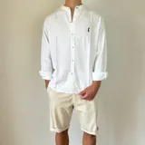 Camisa blanca de lino con cuello mao, manga larga y corte regular. Presenta un pequeño bordado en el pecho.