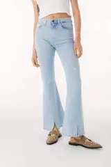 Pantalón de jean azul de corte acampanado con aberturas en el ruedo.