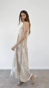 Vestido largo de tirantes finos con estampado de hojas en tonos beige y blanco.