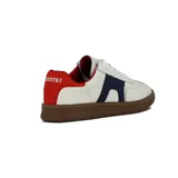 Zapatilla deportiva de caña baja, color blanco, con suela de goma marrón. Presenta detalles en azul marino con borde festoneado en el lateral y refuerzo en el talón de color rojo. Cordones blancos.