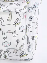 Mochila blanca con estampado de unicornios, arcoíris, corazones y otros motivos infantiles. Tiene doble asa de mano y tiras de mochila ajustables.