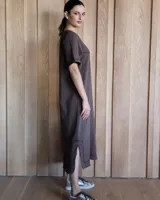 Vestido midi negro con cuello redondo y mangas cortas. Presenta dos bolsillos cuadrados en el pecho y ribetes blancos en cuello, mangas, bolsillos y ruedo.