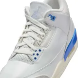 Championes de cuero blancos con detalles en gris y celeste. Presentan la suela color crema y el logo de Air Jordan en la lengüeta y en el talón.