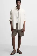 Bermuda regular fit negra confeccionada en tejido de lino. Cintura elástica ajustable con cordón y pliegues frontales. Bolsillos frontales y detalle de bolsillos traseros de plastrón.