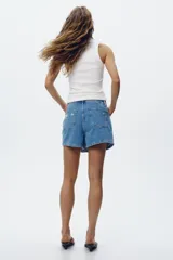 Falda pantalón de jean de tiro alto con cinco bolsillos, efecto lavado y roturas frontales. Cierre frontal con cremallera oculta y botones.