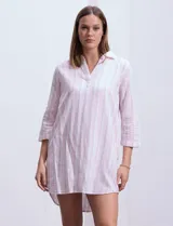 Vestido corto de algodón a rayas verticales rosas y blancas, con cuello solapa y escote en V. Manga 3/4 regulable con presilla y botón.