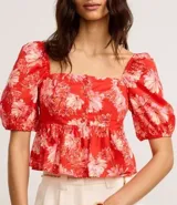 Blusa peplum cropped de tricolina con estampa floral, escote cuadrado, mangas abullonadas cortas y botones delanteros.
