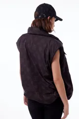 Chaleco negro con estampado de logos, cuello alto, cierre frontal con cremallera y broches a presión ocultos, bolsillos delanteros y cintura ajustable con cordón elástico. Interior de tafeta relleno de guata.