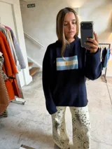 Sweater azul marino de tejido grueso, corte oversize y hombros caídos, con un bordado frontal que representa la bandera de Argentina.