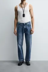 Pantalón de jean celeste de corte flare, con tiro medio, cinco bolsillos, cierre frontal con cremallera y botón, y bajo con acabado irregular.