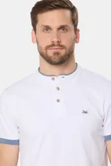 Remera de manga corta color azul grisáceo con cuello mao y tapeta de botones. Los puños de las mangas y el cuello son de color azul marino contrastante. Presenta un pequeño logo bordado en el pecho.