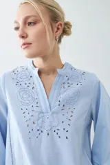 Blusa celeste con escote en V y bordado floral en el frente y en las mangas 3/4.