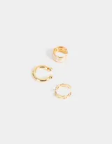Set de tres aros ear cuff dorados. Uno liso, otro con diseño de corazones blancos y otro con diseño de ondas.