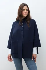 Chaqueta tejida de punto color verde oliva, con cuello alto y cierre frontal de botones a presión. Presenta bolsillos delanteros aplicados y mangas amplias de largo tres cuartos.