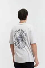 Remera oversize color crudo con efecto acid wash y estampado en la espalda con diseño de serpiente en círculo con texto.