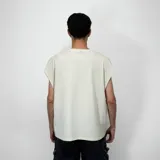 Musculosa de algodón color beige claro, corte oversize con hombros caídos y cuello redondo. Estampado frontal con texto en gris oscuro: "VENEFO® COMPANY" a la izquierda y "004®1994 .CCL™" a la derecha.