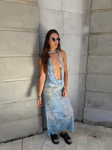 Vestido largo celeste con estampado abstracto en tonos dorados, escote halter y espalda descubierta.