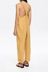 Mono largo de lino color crudo con rayas verticales rojas y azules. Tiene corte recto, escote redondeado pronunciado, tirantes anchos con trabillas para fruncir y espalda nadadora.