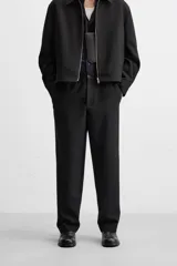 Pantalón negro de corte regular, confeccionado en tejido con viscosa, con cintura elástica, bolsillos frontales y trasero de vivo.