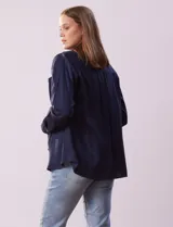 Camisa blanca de lyocell, marca Dash. Tiene cuello con solapa, abertura central con botones, mangas largas regulables con presilla y botón, y dos bolsillos delanteros aplicados.