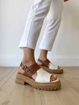 Sandalias de cuero color camel y crudo, con plataforma track y hebilla ajustable.