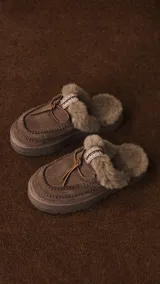 Pantuflas UGG de cuero color marrón con interior de piel sintética y detalle de costuras en contraste.