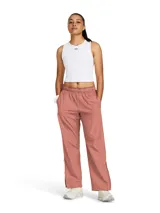 Pantalón deportivo Under Armour Rush OS Woven para mujer, color rosa, de corte holgado, con cintura elástica, bolsillos laterales y cierres en los tobillos. Confeccionado en tejido con infusión de minerales que ayuda a combatir la fatiga.