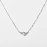 Colgante delicado de bronce con tres piedras brillantes en un diseño sencillo y elegante.