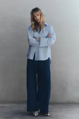 Camisa celeste de popelina de algodón, con cuello solapa, escote pico, manga larga con puños y cierre frontal con botones.