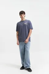 Remera de manga corta color crema con estampado en la espalda que incluye flores azules, texto "All Day Every Day The Good Vibes Crew Mistral" y texto "Feel Good" en el lateral.