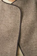 Chaleco marrón con solapas amplias y terminaciones envivadas. Diseño reversible y sin mangas.