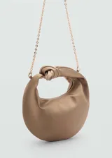 Bolso de mano color beige de tejido satinado con asa superior con nudo decorativo. Tiene cierre de cremallera, forro interior y asa de cadena desmontable.