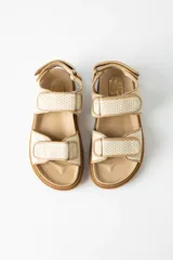 Sandalias planas color beige con tiras de rafia y ajuste con velcro.