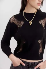 Sweater negro de punto con cuello redondo y mangas largas. Presenta recortes de encaje en la parte superior delantera y en los hombros.