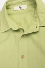 Camisa de manga larga color verde claro, confeccionada en tejido de lino y viscosa, con botones de madera y parche con logo.