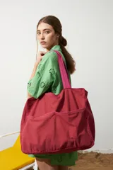 Bolso rígido color rojo con vivos en contraste color fucsia y manijas cortas.