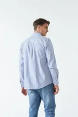 Camisa oxford celeste con rayas verticales blancas, de manga larga y corte regular. Tiene cuello abotonado, bolsillo en el pecho y logo bordado.
