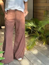 Pantalón ancho color ocre, de tiro medio, confeccionado en lino y algodón. Presenta bolsillos delanteros y traseros con triple pespunte en contratono y remaches.