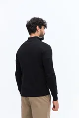 Sweater de tejido liso color verde oscuro, con cuello medio y cierre frontal parcial plateado. Presenta puños y cintura acanalados, y un pequeño logo bordado en el pecho.